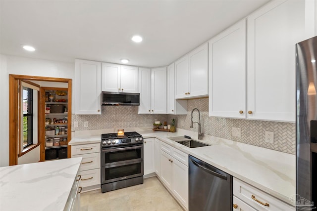 kitchen featuring light stone counters, white cabinets, stainless steel appliances, and sink