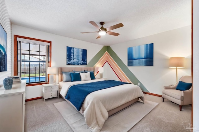 carpeted bedroom featuring ceiling fan and a textured ceiling