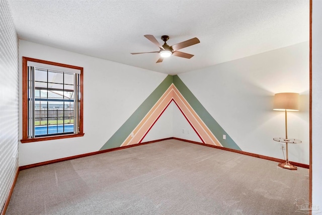 spare room with a textured ceiling, carpet flooring, and ceiling fan