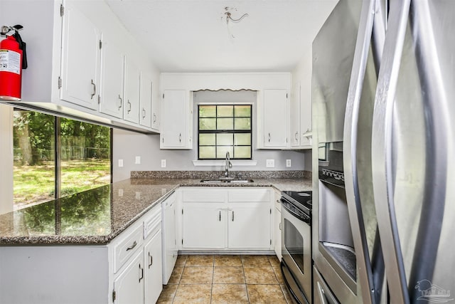 kitchen featuring dark stone countertops, stainless steel appliances, sink, and white cabinets