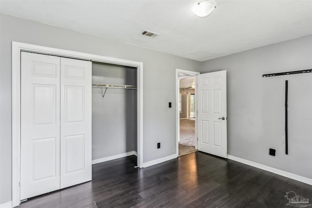 unfurnished bedroom with dark hardwood / wood-style floors, a textured ceiling, and a closet