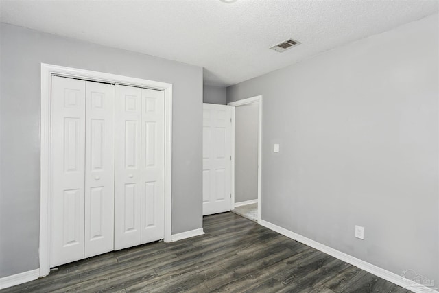 unfurnished bedroom featuring dark hardwood / wood-style floors, a textured ceiling, and a closet