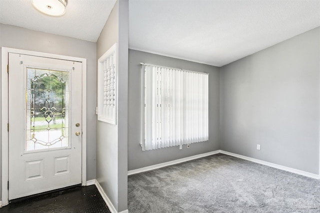 entrance foyer featuring a textured ceiling and dark colored carpet