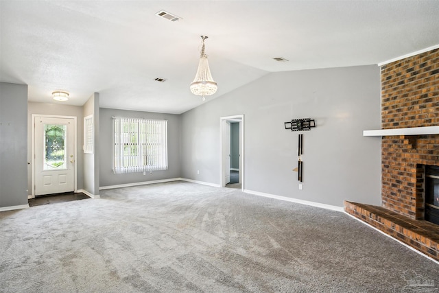 unfurnished living room featuring a brick fireplace, vaulted ceiling, and carpet