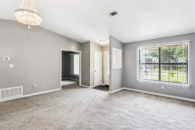 carpeted empty room featuring an inviting chandelier and lofted ceiling