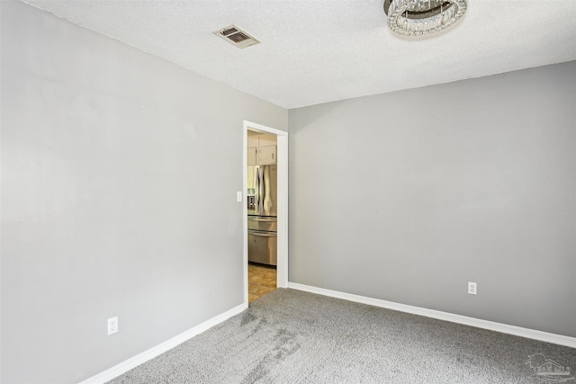 carpeted spare room with a textured ceiling