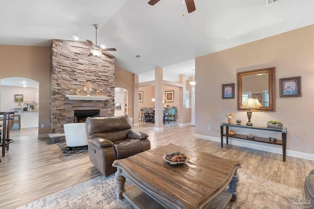 3246 Main St, Navarre, FL 32566 - living room featuring arched walkways, light wood-style flooring, a fireplace, visible vents, and vaulted ceiling
