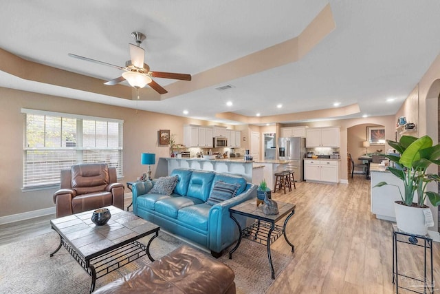 3246 Main St, Navarre, FL 32566 - living area featuring light wood-style floors, a tray ceiling, visible vents, and arched walkways