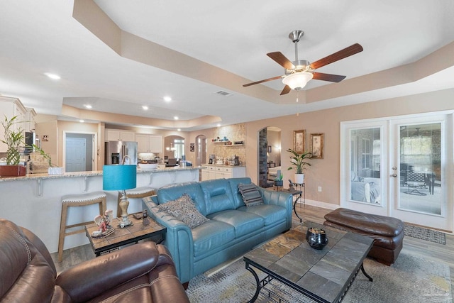 3246 Main St, Navarre, FL 32566 - living room featuring visible vents, a tray ceiling, arched walkways, and wood finished floors