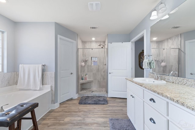 3246 Main St, Navarre, FL 32566 - full bath with a garden tub, wood finished floors, vanity, visible vents, and a shower stall