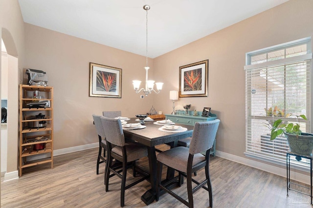 3246 Main St, Navarre, FL 32566 - dining area featuring light wood-style floors, baseboards, arched walkways, and an inviting chandelier