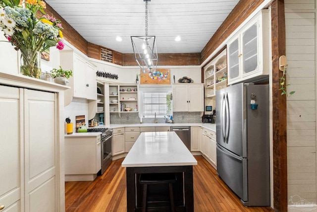 kitchen featuring open shelves, appliances with stainless steel finishes, wood finished floors, and light countertops