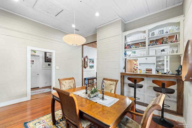 dining area with baseboards, wooden walls, wood ceiling, and wood finished floors