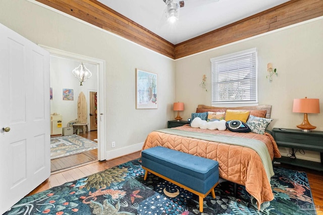 bedroom with ceiling fan with notable chandelier, wood finished floors, and baseboards