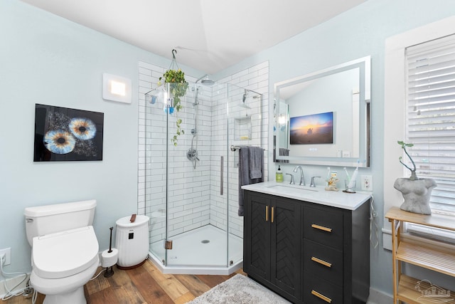 full bathroom featuring vanity, a shower stall, toilet, and wood finished floors