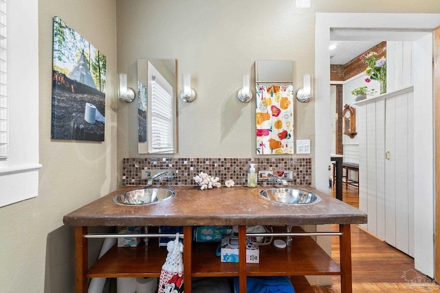 bathroom featuring double vanity, wood finished floors, tasteful backsplash, and a sink