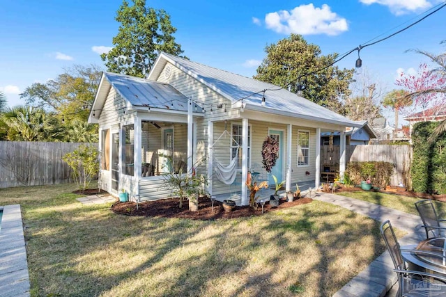 bungalow with metal roof, a sunroom, a front yard, and fence