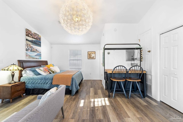 bedroom with a notable chandelier, wood finished floors, and a closet