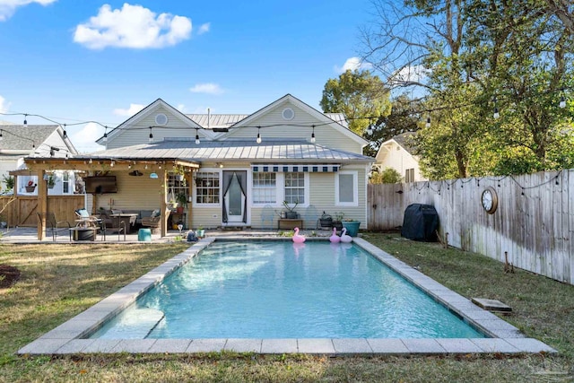 back of property with a fenced in pool, a yard, a fenced backyard, a patio area, and metal roof