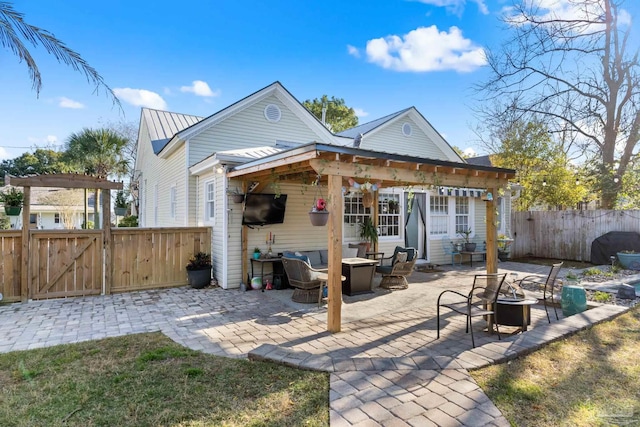 rear view of house with metal roof, a gate, fence, and an outdoor fire pit