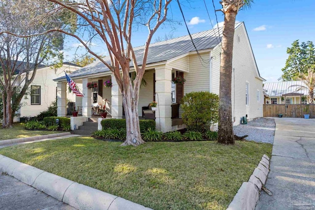 view of front facade with metal roof, a porch, a front yard, and fence