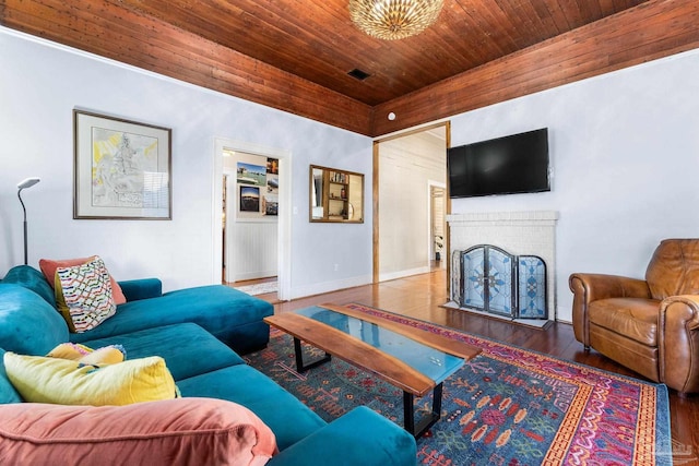 living area with wood finished floors, baseboards, visible vents, wooden ceiling, and a brick fireplace