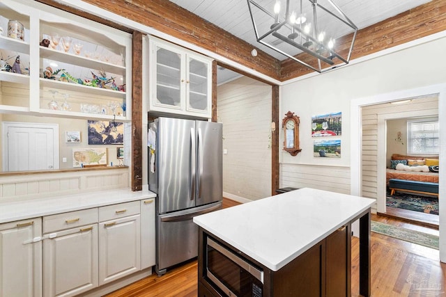 kitchen with light countertops, glass insert cabinets, appliances with stainless steel finishes, light wood-type flooring, and a center island