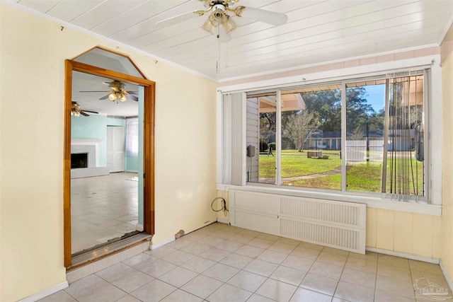 spare room featuring radiator, ceiling fan, light tile patterned floors, ornamental molding, and wood ceiling