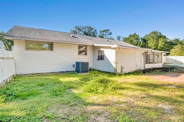 back of property featuring a sunroom, cooling unit, and a lawn