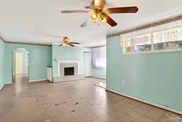 unfurnished living room featuring a tiled fireplace, ceiling fan, and a textured ceiling