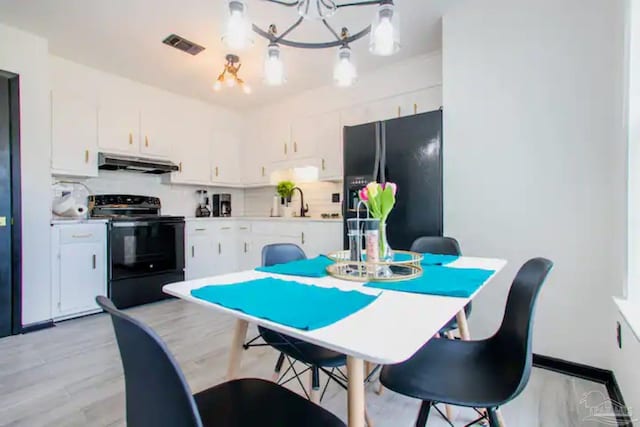 kitchen with hanging light fixtures, white cabinets, black appliances, and a chandelier