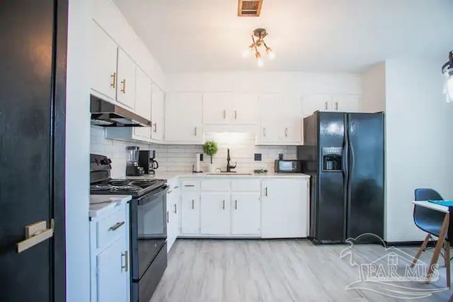 kitchen featuring tasteful backsplash, black appliances, sink, white cabinetry, and light hardwood / wood-style flooring