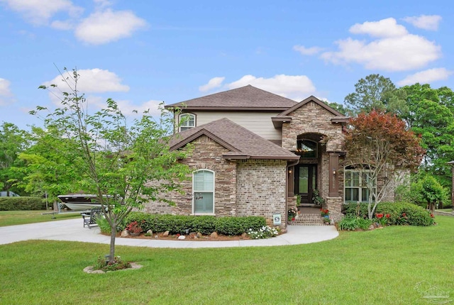 view of front of home featuring a shingled roof, a front lawn, and stone siding