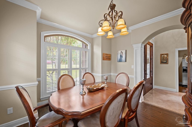dining room featuring ornate columns, crown molding, a notable chandelier, and arched walkways