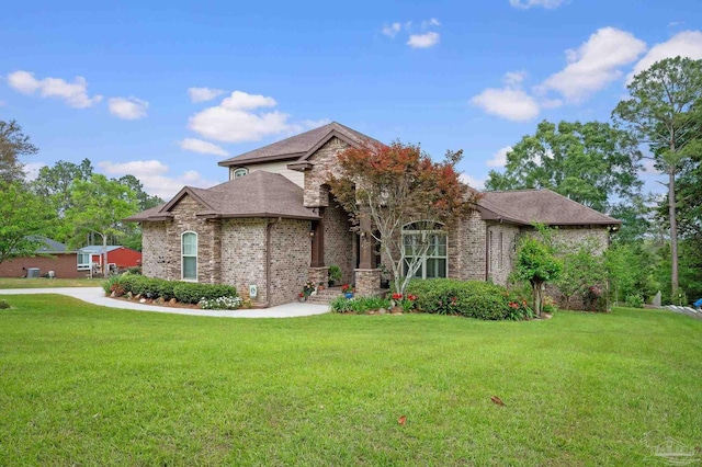 view of front of house with brick siding, a shingled roof, a front yard, and stone siding