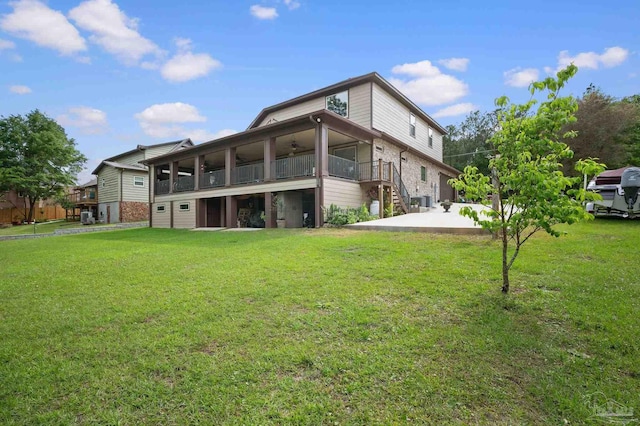 back of house with stairway, ceiling fan, and a yard