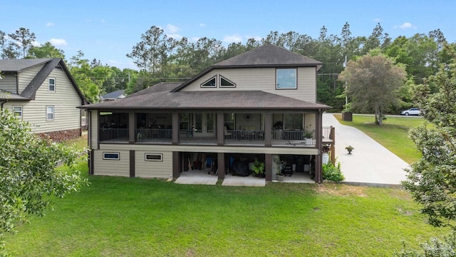 back of property featuring a lawn, roof with shingles, and a patio area