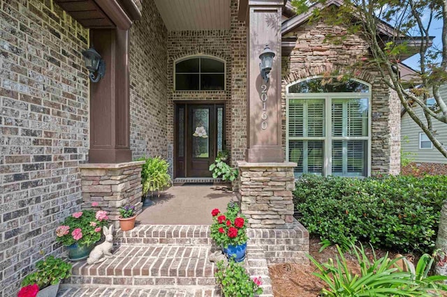 property entrance featuring a porch, stone siding, and brick siding