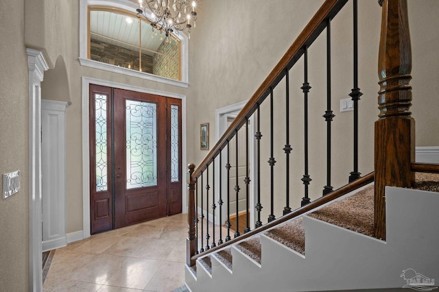 foyer entrance featuring a towering ceiling, stairway, a chandelier, and baseboards