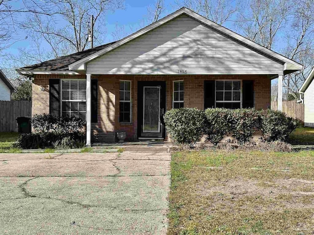 bungalow-style home with a porch, brick siding, and fence