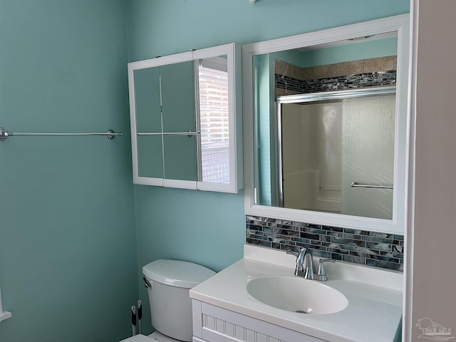 bathroom featuring a shower with door, vanity, toilet, and decorative backsplash