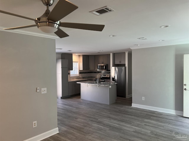 kitchen with tasteful backsplash, gray cabinetry, ornamental molding, a kitchen island with sink, and stainless steel appliances