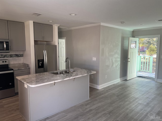 kitchen featuring appliances with stainless steel finishes, gray cabinets, a kitchen island with sink, and sink