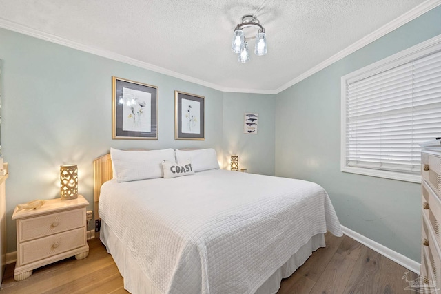 bedroom with ornamental molding, light hardwood / wood-style floors, and a textured ceiling