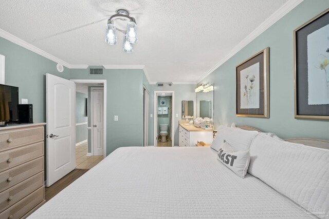 bedroom with hardwood / wood-style floors, ensuite bath, ornamental molding, and a textured ceiling