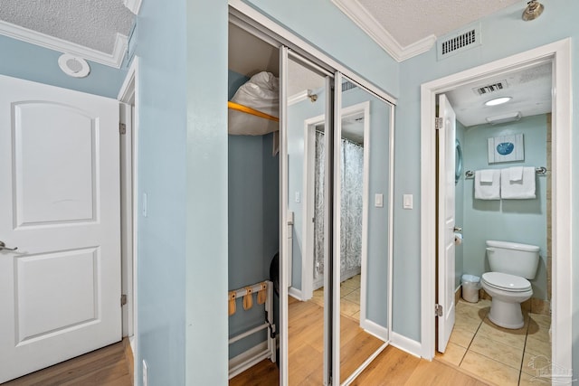 bathroom featuring crown molding, a textured ceiling, wood-type flooring, and toilet