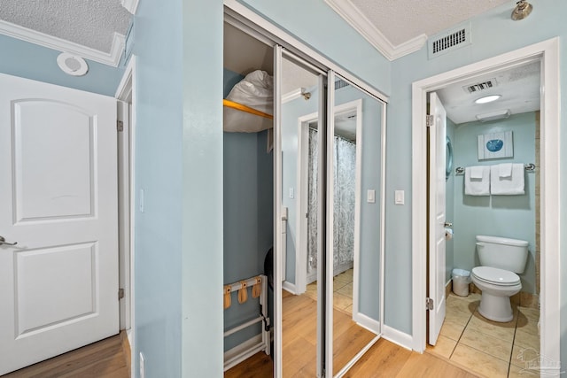 bathroom with crown molding, wood-type flooring, a textured ceiling, and toilet