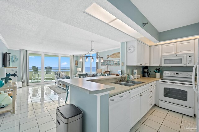 kitchen with white appliances, sink, kitchen peninsula, hanging light fixtures, and light tile patterned floors