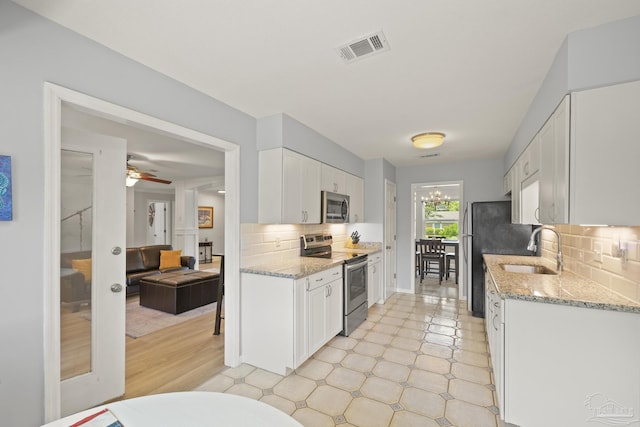 kitchen with tasteful backsplash, stainless steel appliances, white cabinets, a sink, and visible vents