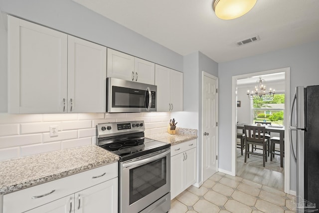 kitchen featuring an inviting chandelier, stainless steel appliances, tasteful backsplash, visible vents, and white cabinetry